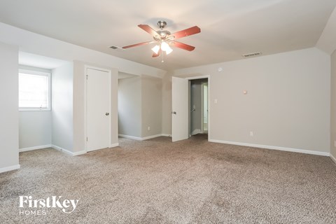 a spacious living room with carpet and a ceiling fan