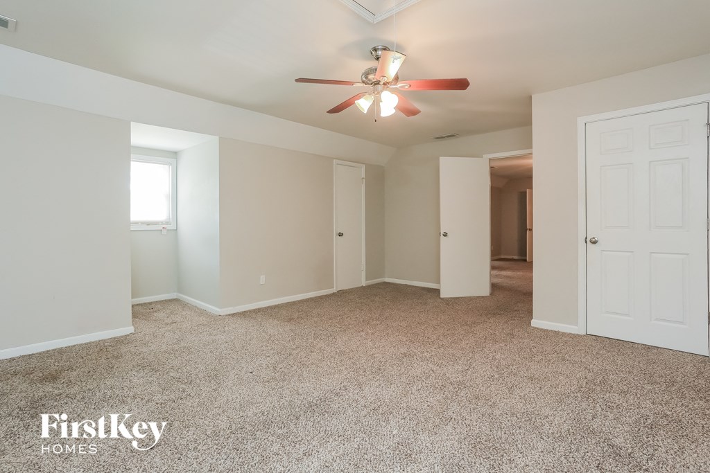 a master bedroom with carpet and a ceiling fan