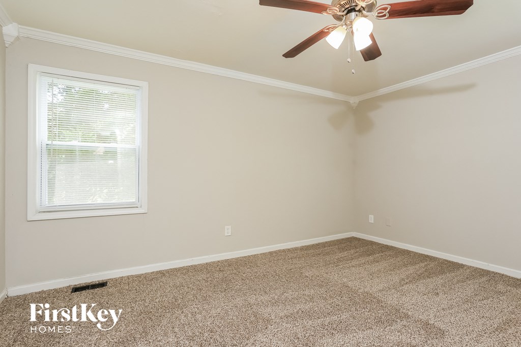 the bedroom has a ceiling fan and beige carpet