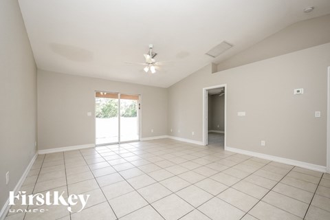 A spacious room with a sliding glass door leading to a balcony.
