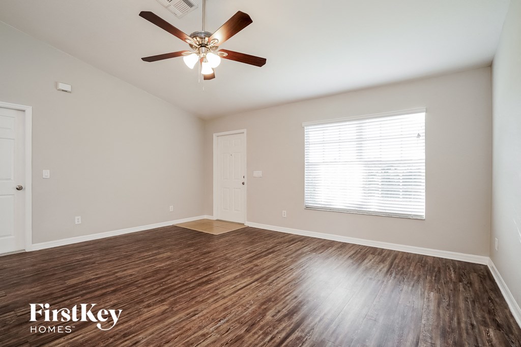 A room with a ceiling fan and wooden flooring.