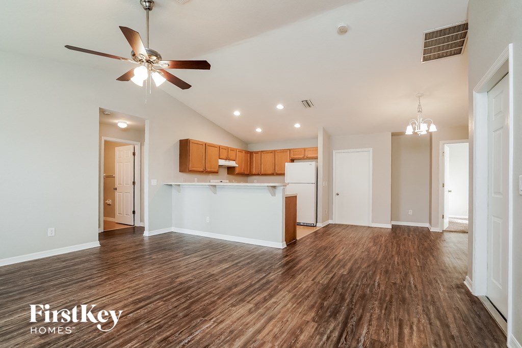 A spacious room with wooden flooring and a ceiling fan.