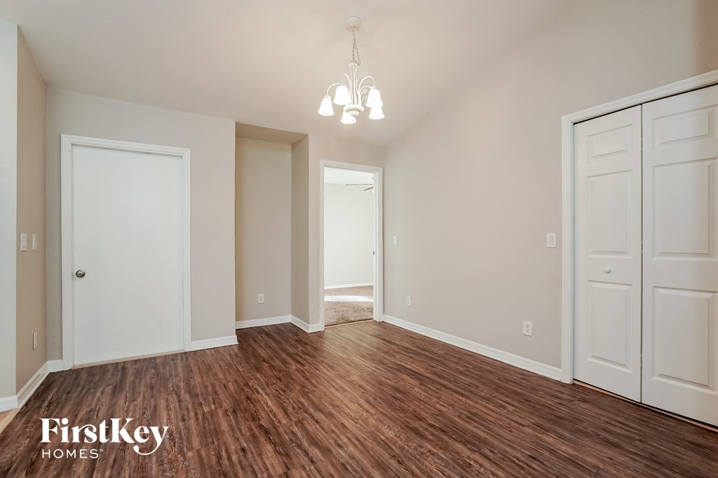 A room with wooden floors and white walls, with a chandelier hanging from the ceiling.