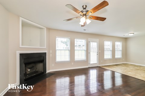 A spacious living room with a fireplace and a ceiling fan.