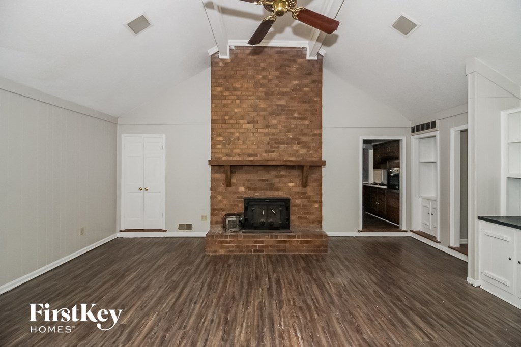a living room with a brick fireplace and wooden floors