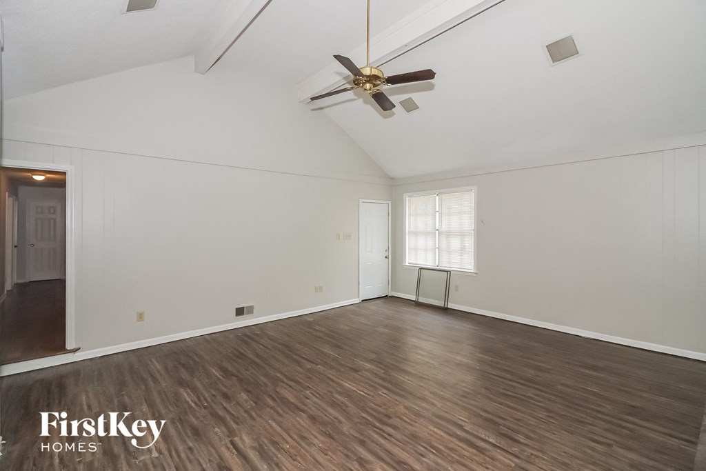 the living room of a home with white walls and a ceiling fan