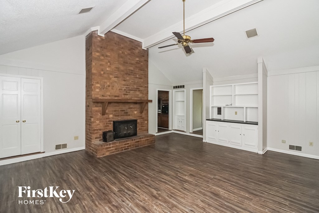a living room with a brick fireplace and a ceiling fan