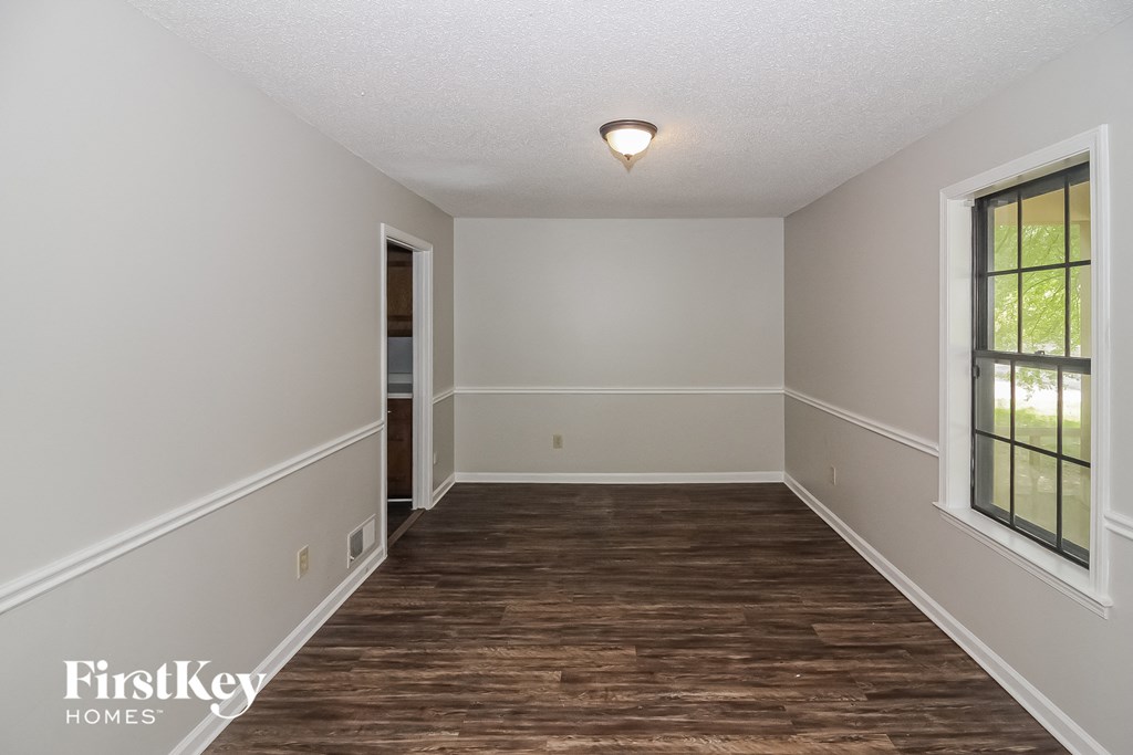 the spacious living room with hardwood flooring and white walls