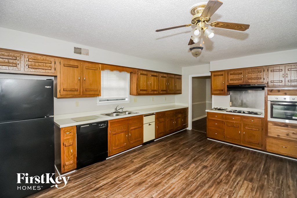 a kitchen with wooden cabinets and black appliances and a ceiling fan
