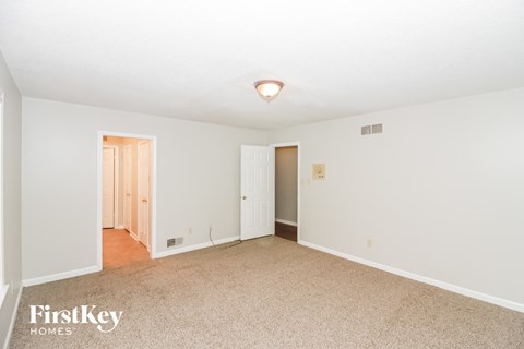 a spacious living room with carpet and white walls