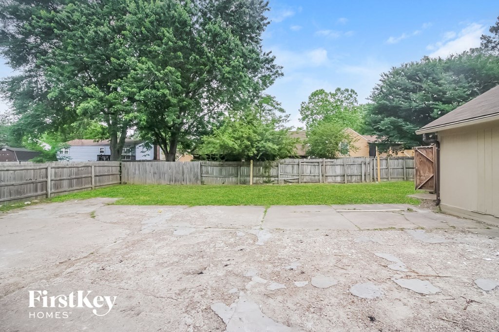 a backyard with a fence and a grassy area and a driveway