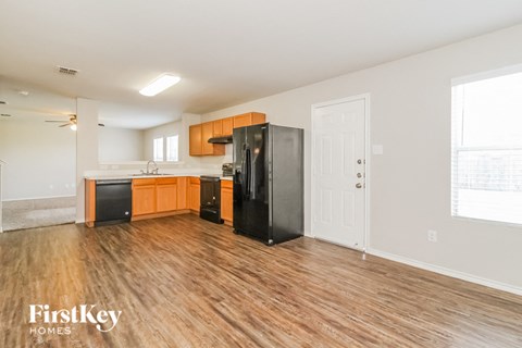 a kitchen with wood flooring and a black refrigerator