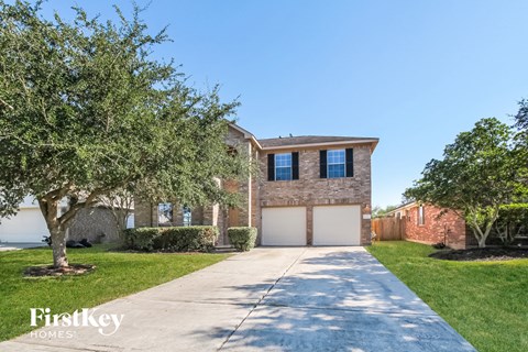 a large brick house with a white garage door and a tree
