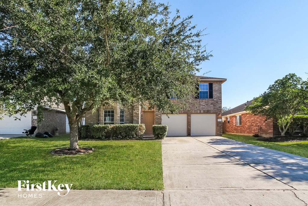 a house with a driveway and a tree in front of it