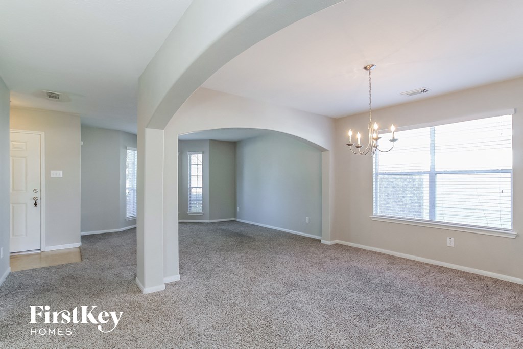 an empty living room with a chandelier and a large window