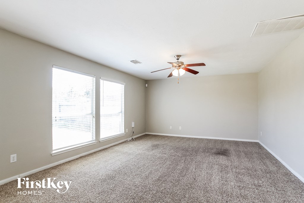 an empty living room with a ceiling fan and a large window