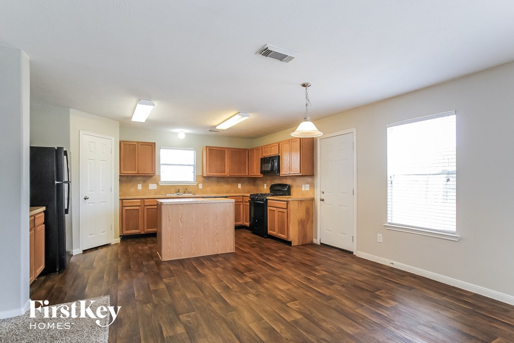 an empty kitchen with wood flooring and a large window