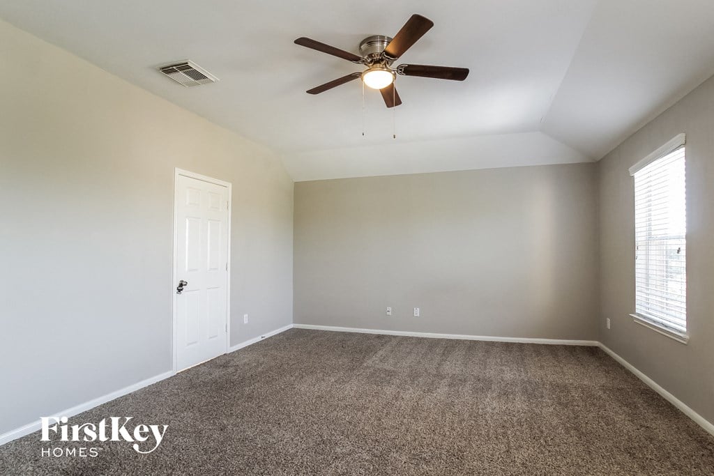 an empty living room with a ceiling fan and a carpet