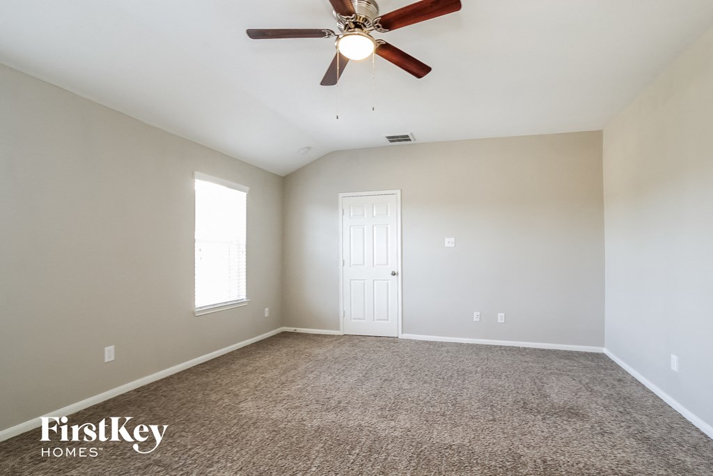 an empty living room with a ceiling fan and a white door