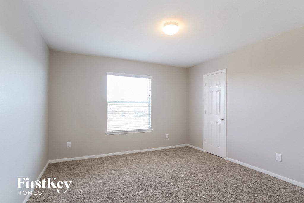 a bedroom with carpet and a window and a white door