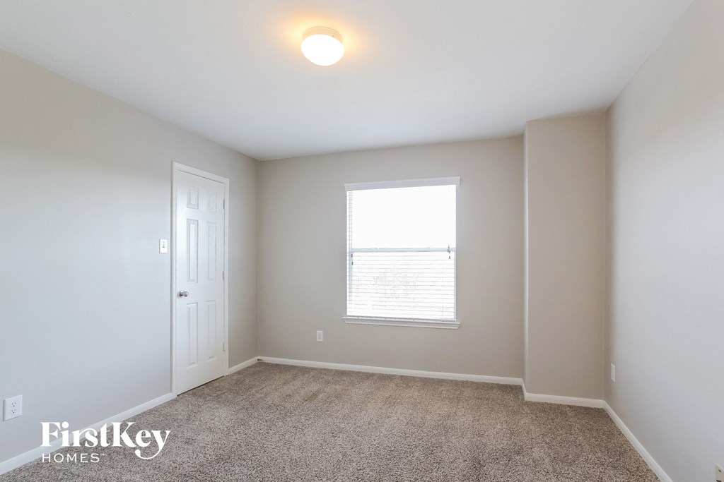 a bedroom with carpet and a window and a white door