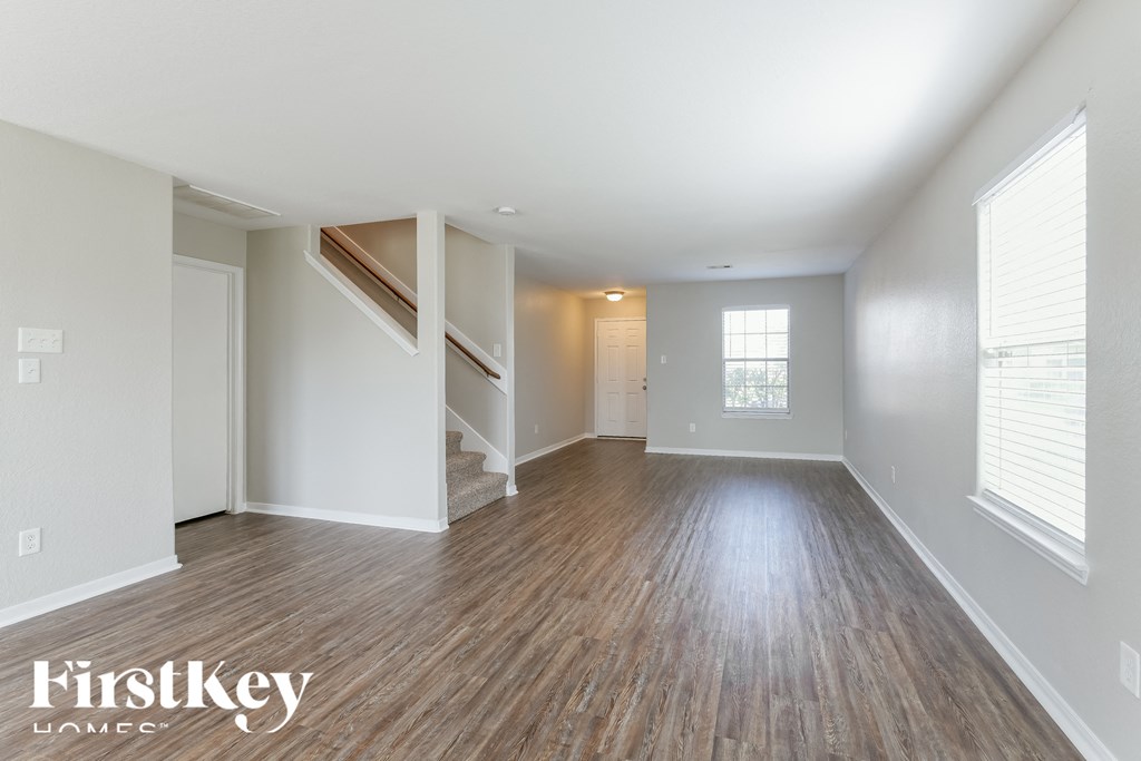 an empty living room with wood floors and white walls