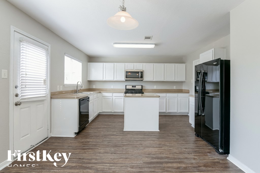 a white kitchen with white cabinets and black appliances