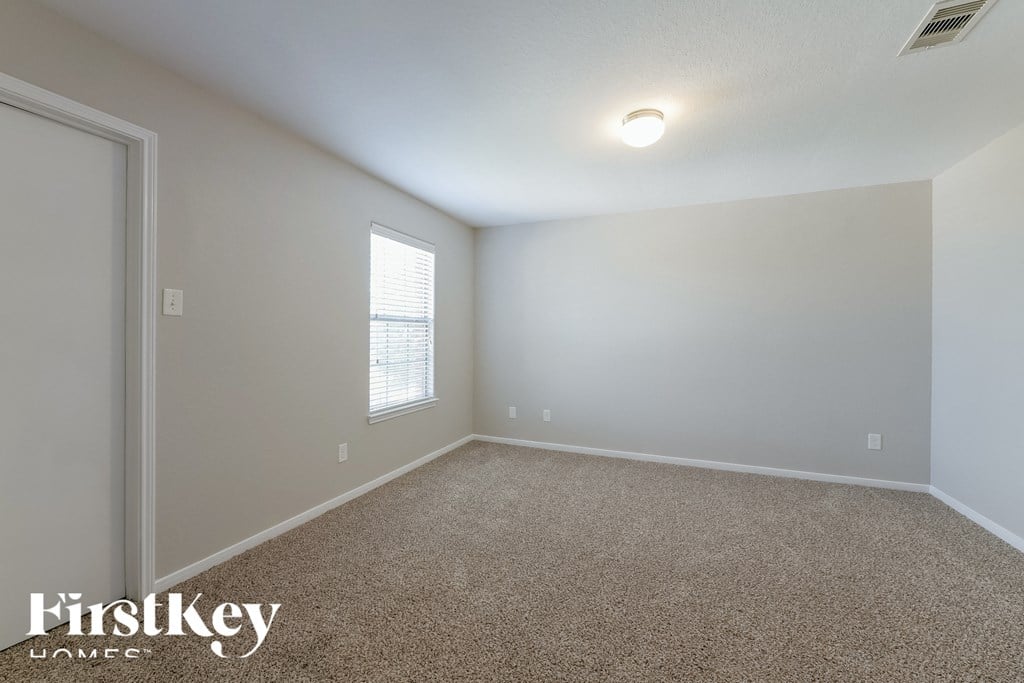 a bedroom with a carpeted floor and a window