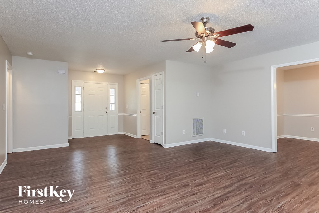 A spacious room with a ceiling fan and wooden flooring.