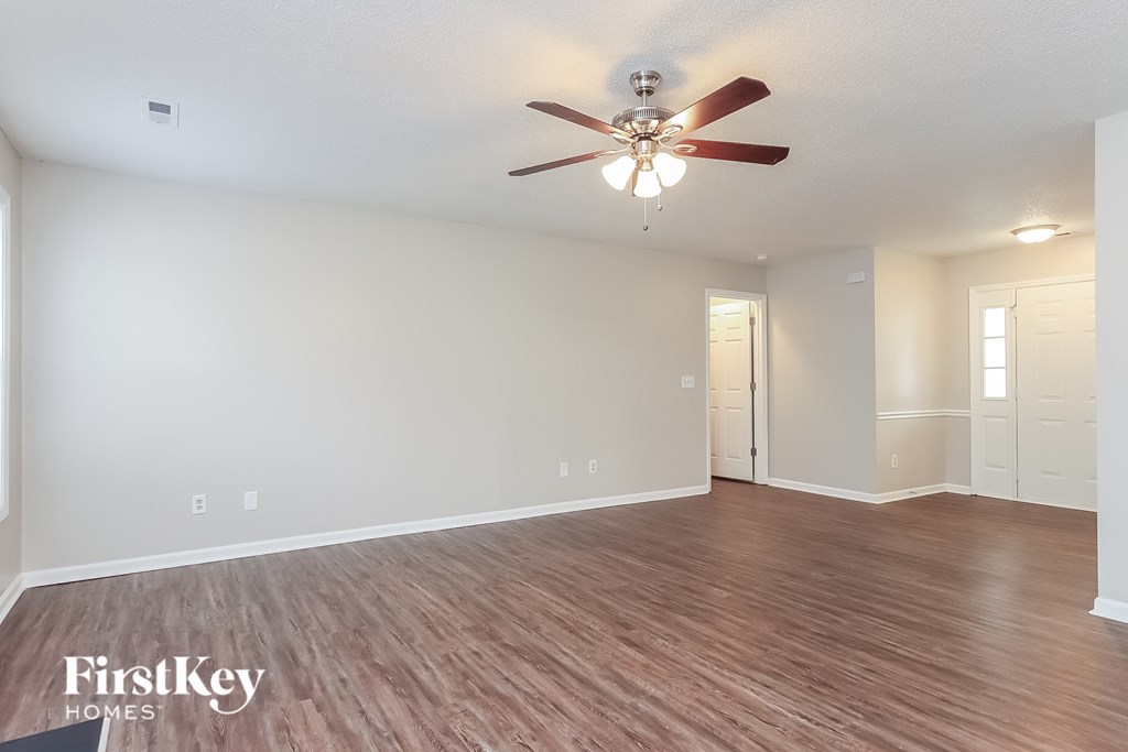 A room with a ceiling fan and wooden flooring.