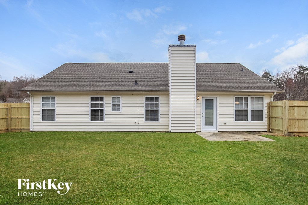 A white house with a chimney and a grassy yard.