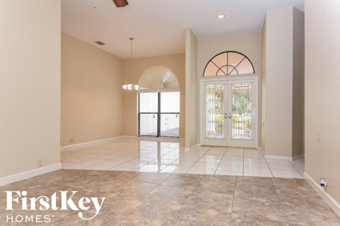 an empty living room with a large tile floor and a glass door