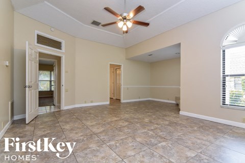 an empty living room with a ceiling fan and a tile floor
