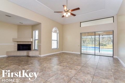 an empty living room with a fireplace and a ceiling fan