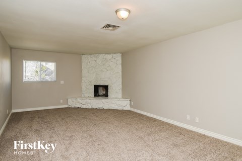a living room with a fireplace and beige carpet