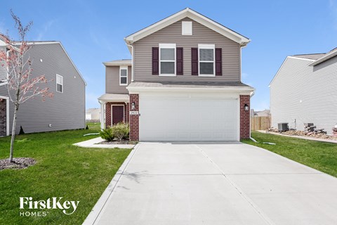 a house with a white driveway in front of a lawn