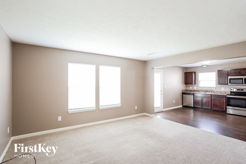 an empty living room with a kitchen in it