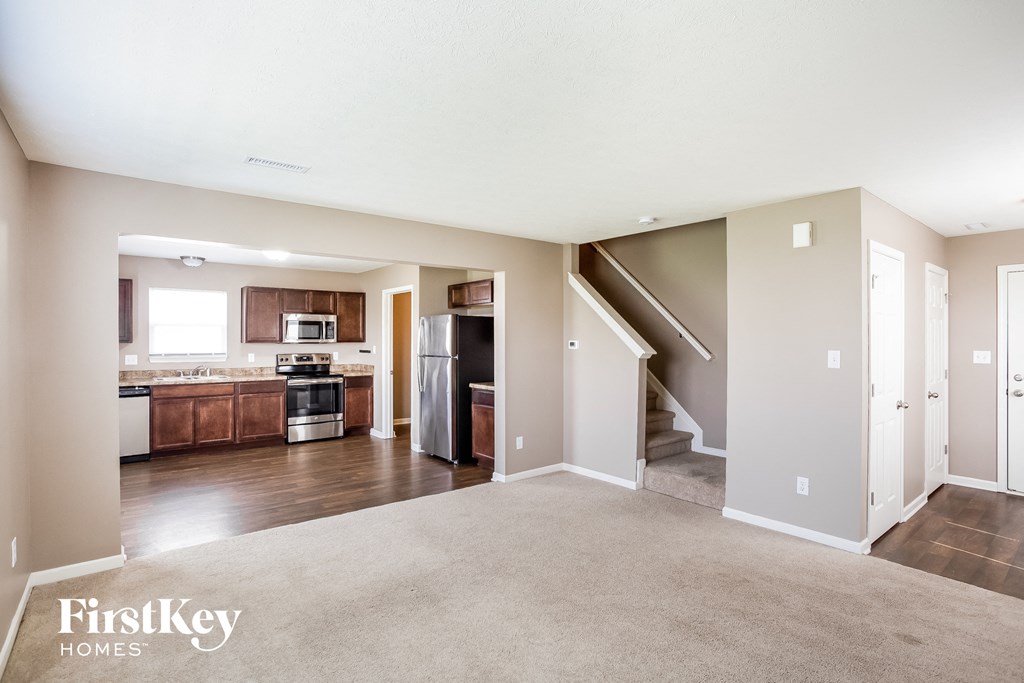 an empty living room with a kitchen and stairs