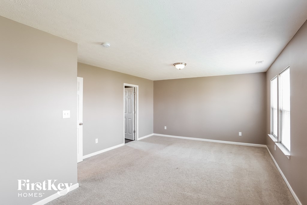 a spacious living room with white carpet and a door to a closet