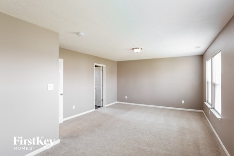 a spacious living room with white carpet and a door to a closet