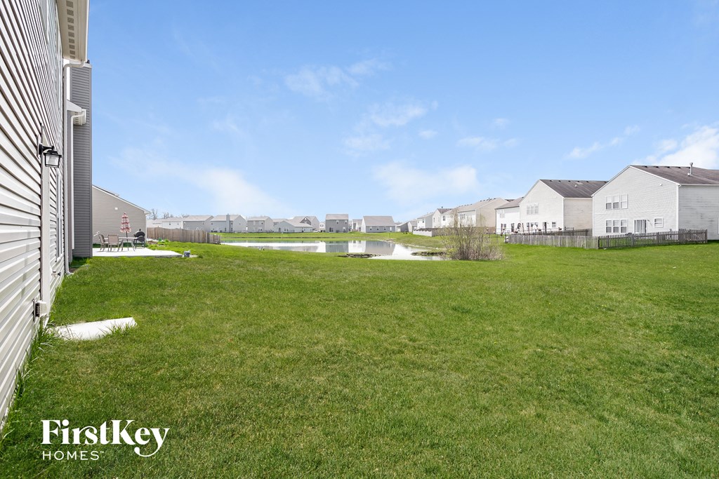 the backyard of a house with a lawn and a pond