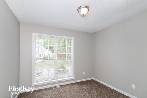 a bedroom with a large window and a carpet