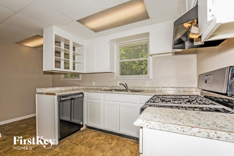a kitchen with white cabinets and granite counter tops and a stove top oven