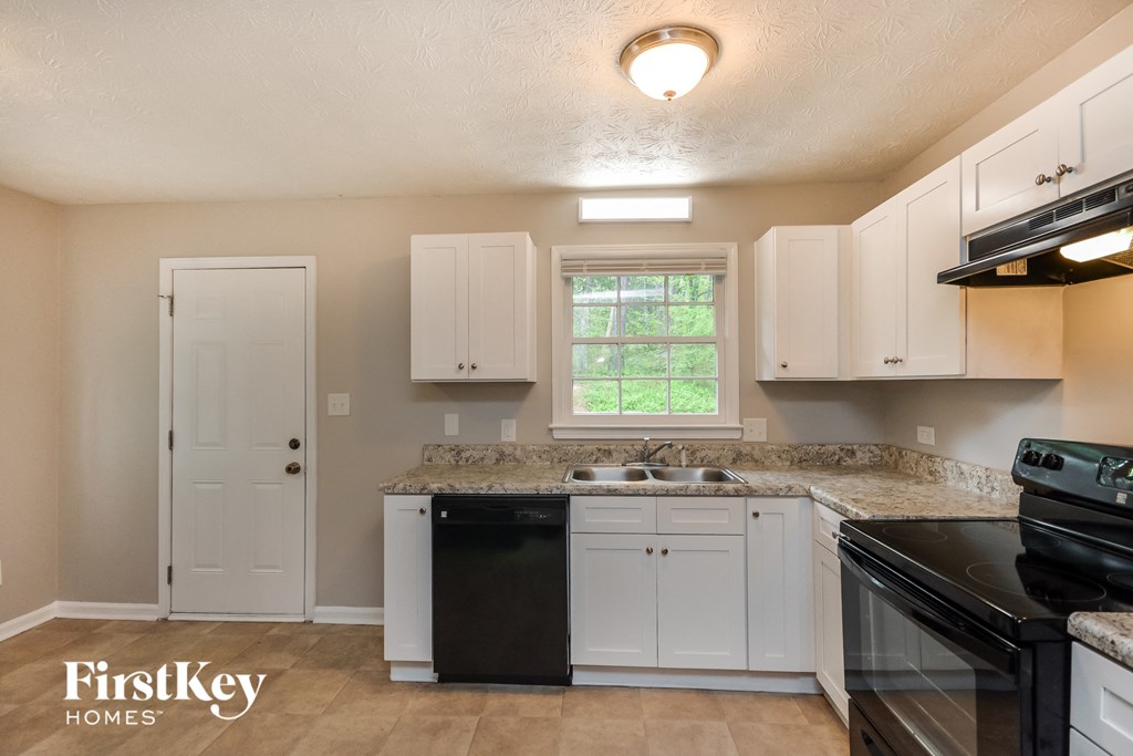 a kitchen with white cabinets and black appliances and a sink