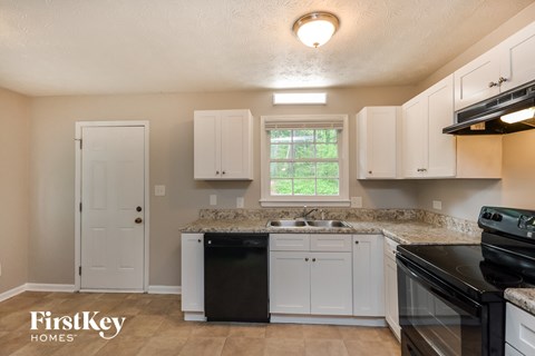 a kitchen with white cabinets and black appliances and a sink