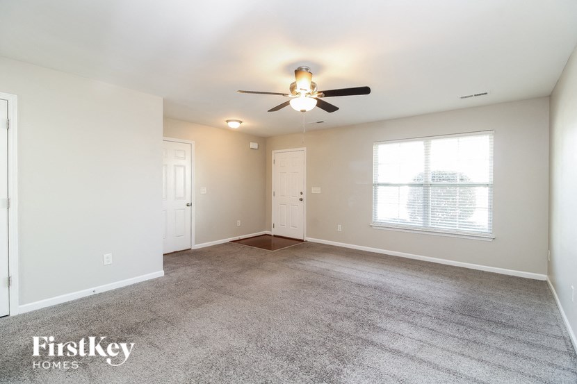 A spacious room with a ceiling fan and carpeted floor.
