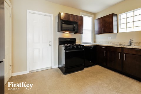 A kitchen with a black stove top oven and a white door.