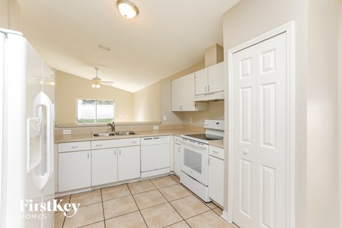 a kitchen with white cabinets and appliances and a white door