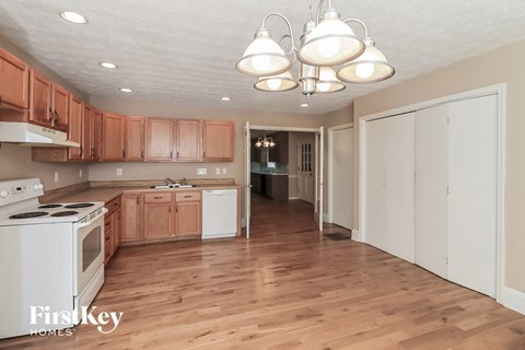 a kitchen with wood flooring and white appliances and wooden cabinets