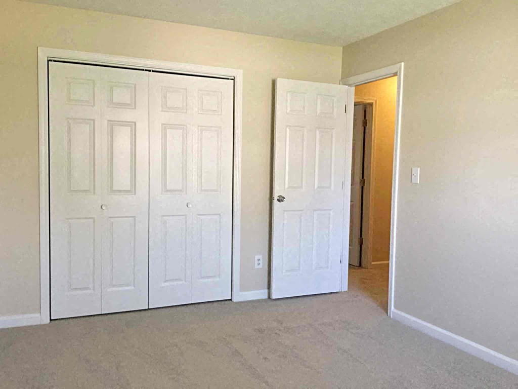 A room with two white doors, one of which is open.